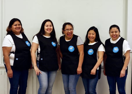 A photo of some of the worker-owners of Dulce Hogar Cleaning Cooperative. They are smiling and wearing their uniforms.