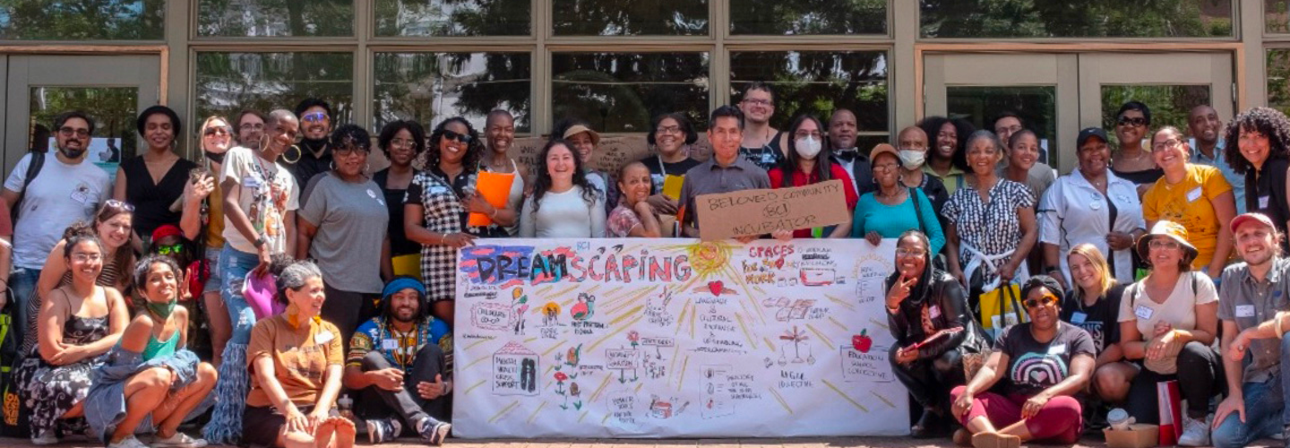 A large group of people pose for a photo outside of a building. A large chart that says "Dreamscaping" sits in the middle of the group. A large group of people pose for a photo outside of a building. A large chart that says "Dreamscaping" sits in the middle of the group.