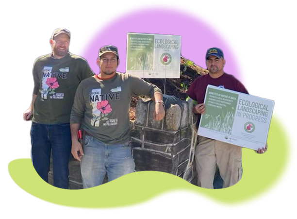 A photograh of worker owners of Swamp Rose Co-op. They stand by some supplies while wearing t-shirts highlighting native plants and holding signs about ecological landscaping. A photograh of worker owners of Swamp Rose Co-op. They stand by some supplies while wearing t-shirts highlighting native plants and holding signs about ecological landscaping.